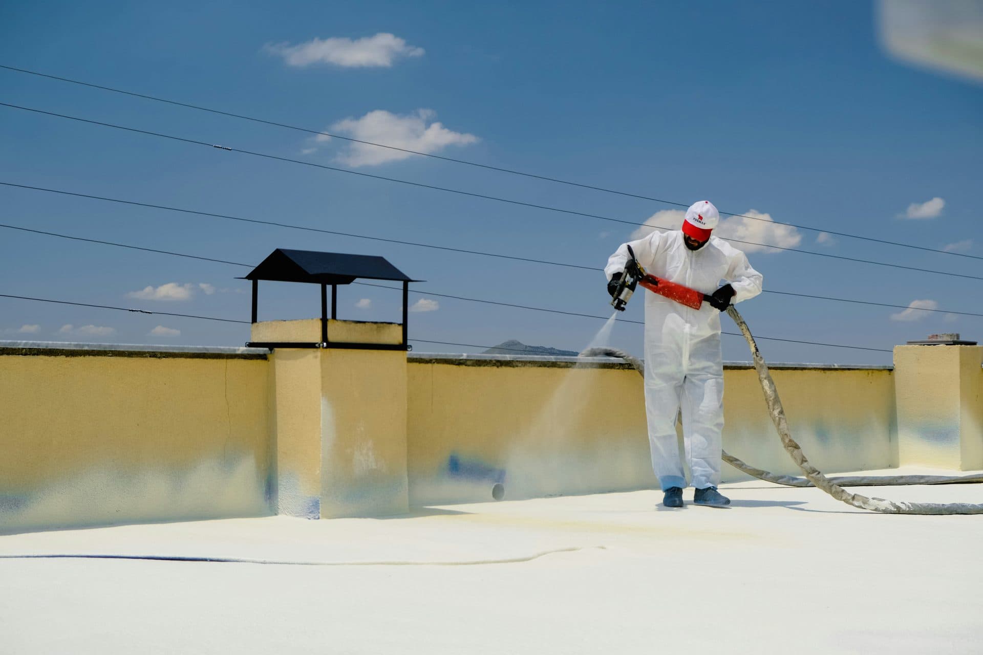Worker applying spray roof coating on a flat roof
